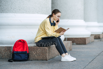 girl with laptop, papers and books near college