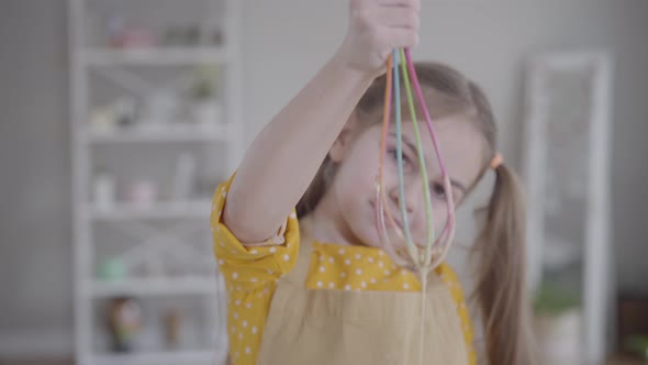 Portrait of Charming Little Girl with Brown Eyes Holding Whisk. Focus Changes From Child's Face To