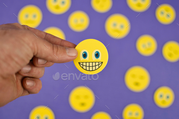 happy emoji between sad emojis on purple background