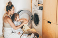 Mother and child girl little helper loading washing machine. - PhotoDune Item for Sale