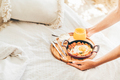 Woman puts breakfast tray loaded with egg and juice on bed. - PhotoDune Item for Sale