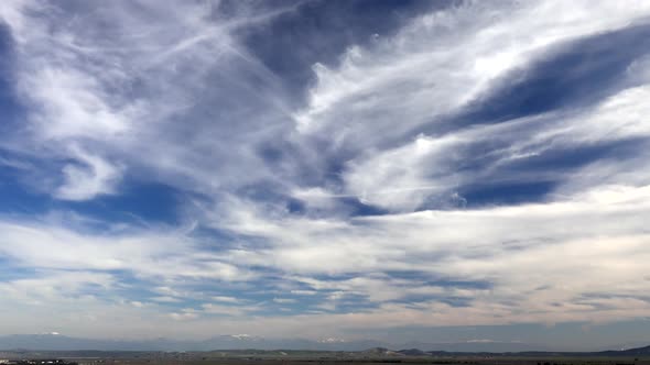 Cirrus Clouds Over the Large Plain Surrounded by Snowy Mountains