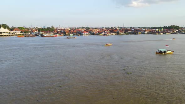 Colorful rooftops of Palembang city while flying over Musi river with sailing boats