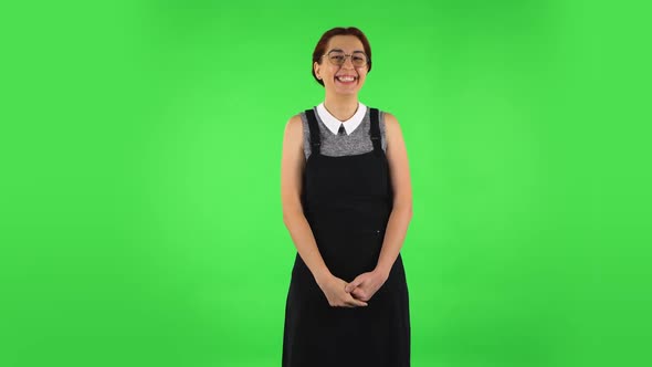 Funny Girl in Round Glasses Is Laughing While Looking at Camera. Green Screen