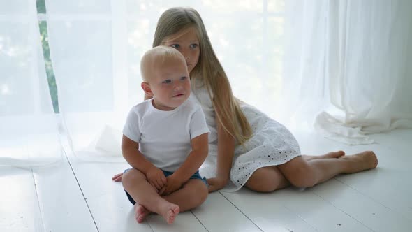 Sister in a White Dress with Her Brother Sitting