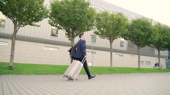 Rear view Asian tourist businessman walks public transport building with luggage