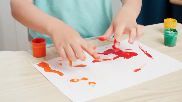 Closeup of Little Boy Painting with Colorful Gouache Paint on White Paper