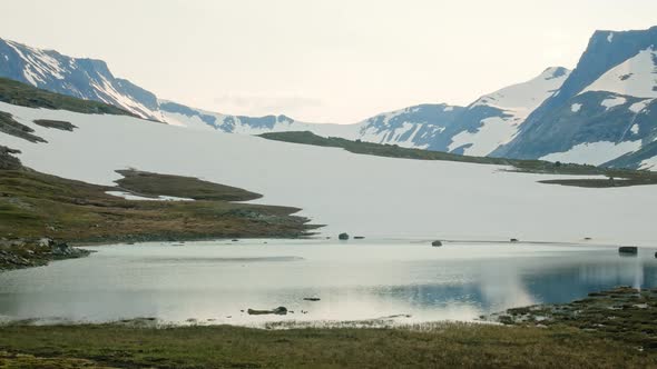 Beautiful calm lake by the white mountains of Sylarna, Sweden -Wide panning