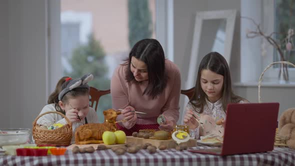 Front View Positive Caucasian Woman and Girls Coloring Eggs on Easter Sunday Watching Online Recipe