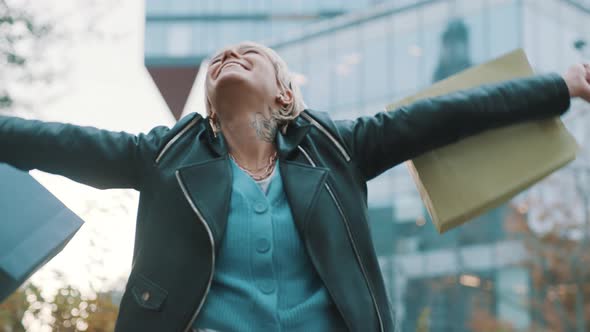 Happy Young Woman with Shopping Bags Laughing Excited in Front of the Shopping Mal