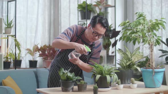 Asian Man Watering Plants At Home