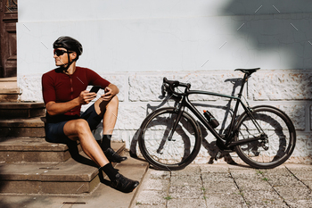  looking aside while sitting on stairs with modern smartphone in hands. Concept of cycling, people and gadgets.