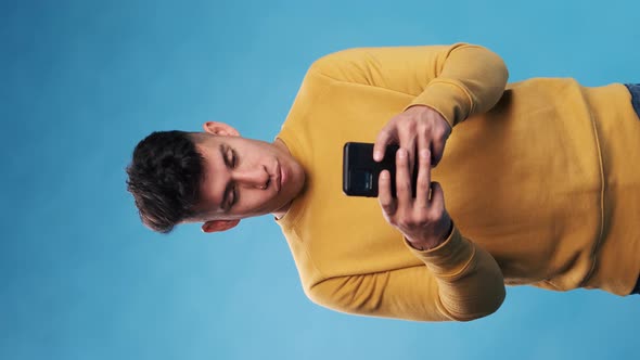 Man typing on his mobile phone while standing on an isolated background.