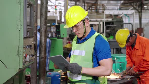 Group of Factory Workers Using Machine Equipment in Factory Workshop