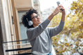 Beautiful woman taking photos with her smartphone while listening to music standing in the balcony - PhotoDune Item for Sale