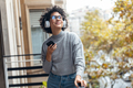 Beautiful woman using her smartphone while listening to music standing in the balcony at home. - PhotoDune Item for Sale