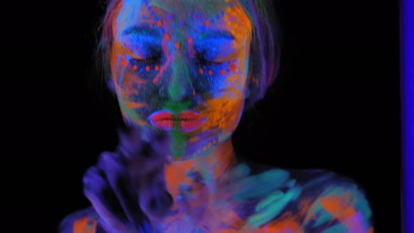 A Magical Space Girl with UV Drawings on Her Face and Body in the Dark