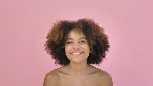 Portrait of a Cute African American Woman Looking Into the Camera and Smiling on a Pink Background