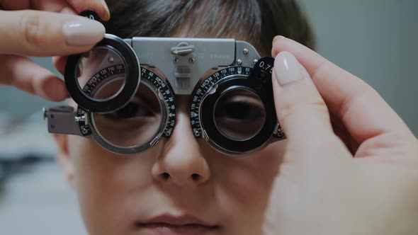 Ophthalmologist Examining Little Boy Inserting a Lens Into Lens Testing Eye Glasses Frame