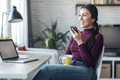 Business woman sending messages with her mobile phone while working and drinking coffe at home. - PhotoDune Item for Sale
