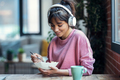 Beautiful young woman listening music with headphones while having healthy breakfast at home. - PhotoDune Item for Sale