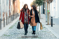 Two beautiful friends talking and having fun while walking on the city street with shopping bag. - PhotoDune Item for Sale
