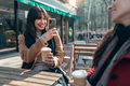 Two attractive friends enjoying coffee while taking a photo with smartphone sitting on a terrace - PhotoDune Item for Sale