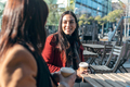 Two attractive friends enjoying coffee together while talking and laughing sitting on a terrace - PhotoDune Item for Sale