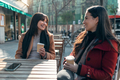 Two attractive friends enjoying coffee together while talking and laughing sitting on a terrace - PhotoDune Item for Sale