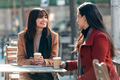 Two attractive friends enjoying coffee together while talking and laughing sitting on a terrace - PhotoDune Item for Sale
