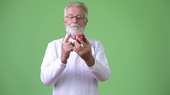 Handsome Senior Bearded Man Doctor Against Green Background