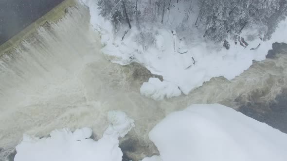 Bird's eye view of river flowing in freezing winter filmed by drone flying down