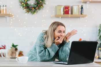 A woman shocked with happiness rejoiced looking at a laptop monitor at home during the New Year and