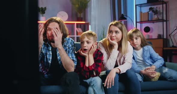 Family of four Persons-Mother, Father, Son and Daughter Watching Bored Film on TV at Home