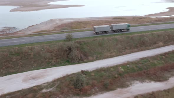 Aerial View of a Truck Hauling a Trailer Driving Along a Shoreline Highway