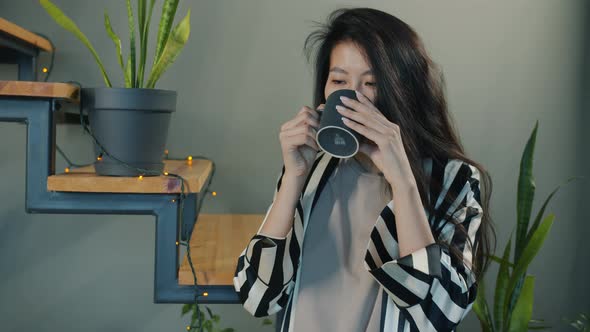 Happy Asian Woman Drinking Coffee in Modern Apartment Smiling Enjoying Morning