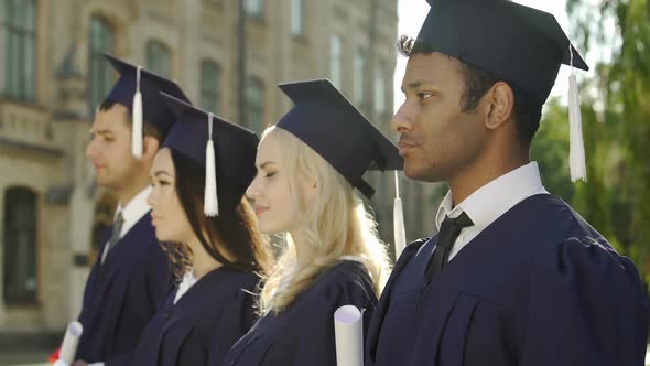 Graduate Students in Academic Regalia Standing in Line and Listening to Speech