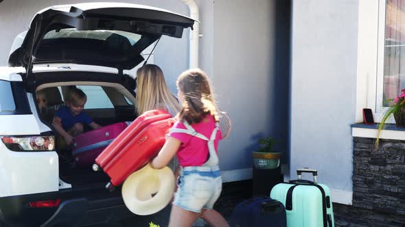 A Woman with Her Daughter Loading the Luggage in the Car