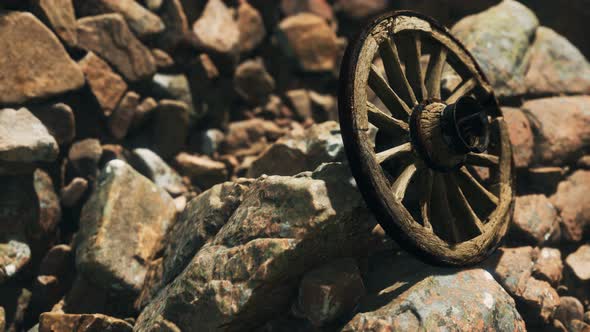 Old Wooden Wheel on Rocks alt