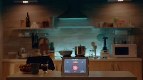 Smart Application on Tablet Placed on Kitchen Desk in Empty House