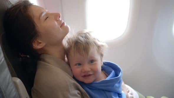 Mother Looks Out an Airplane Window Holding a Baby