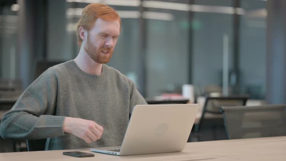 Young Man Having Back Pain While Using Laptop in Office