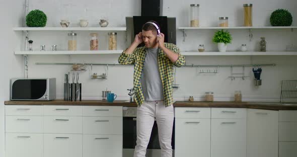 Young Attractive Man Is Dancing and Listening Music in His Kitchen