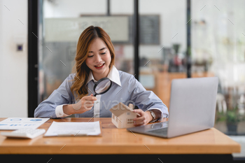 , mortgage loan or new house. Woman with magnifying glass over a wooden house at her office.