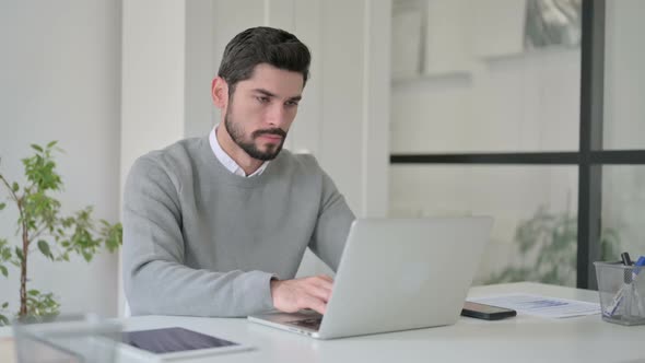 Young Man Shaking Head As No Sign While Using Laptop in Office