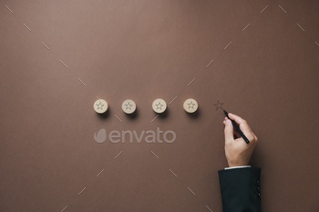 Four stars drawn on wooden cut circles with a hand of a businessman drawing the fifth one