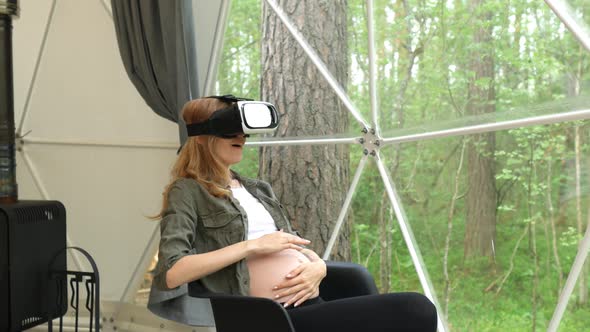 pregnant woman in virtual reality glasses plays with her stomach while
