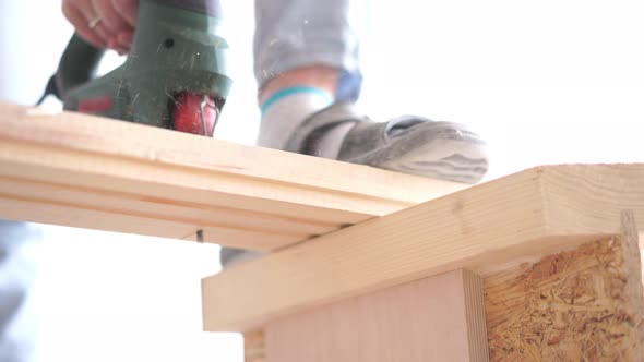 Man Sawing a Wooden Board with an Electric Jigsaw Closeup alt