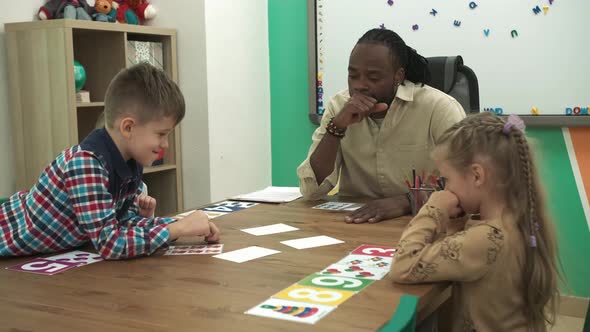 African American Teacher Teaches a Group of Children in a Classroom