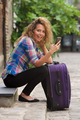 Side portrait happy travel woman sitting on street with bag and phone - PhotoDune Item for Sale